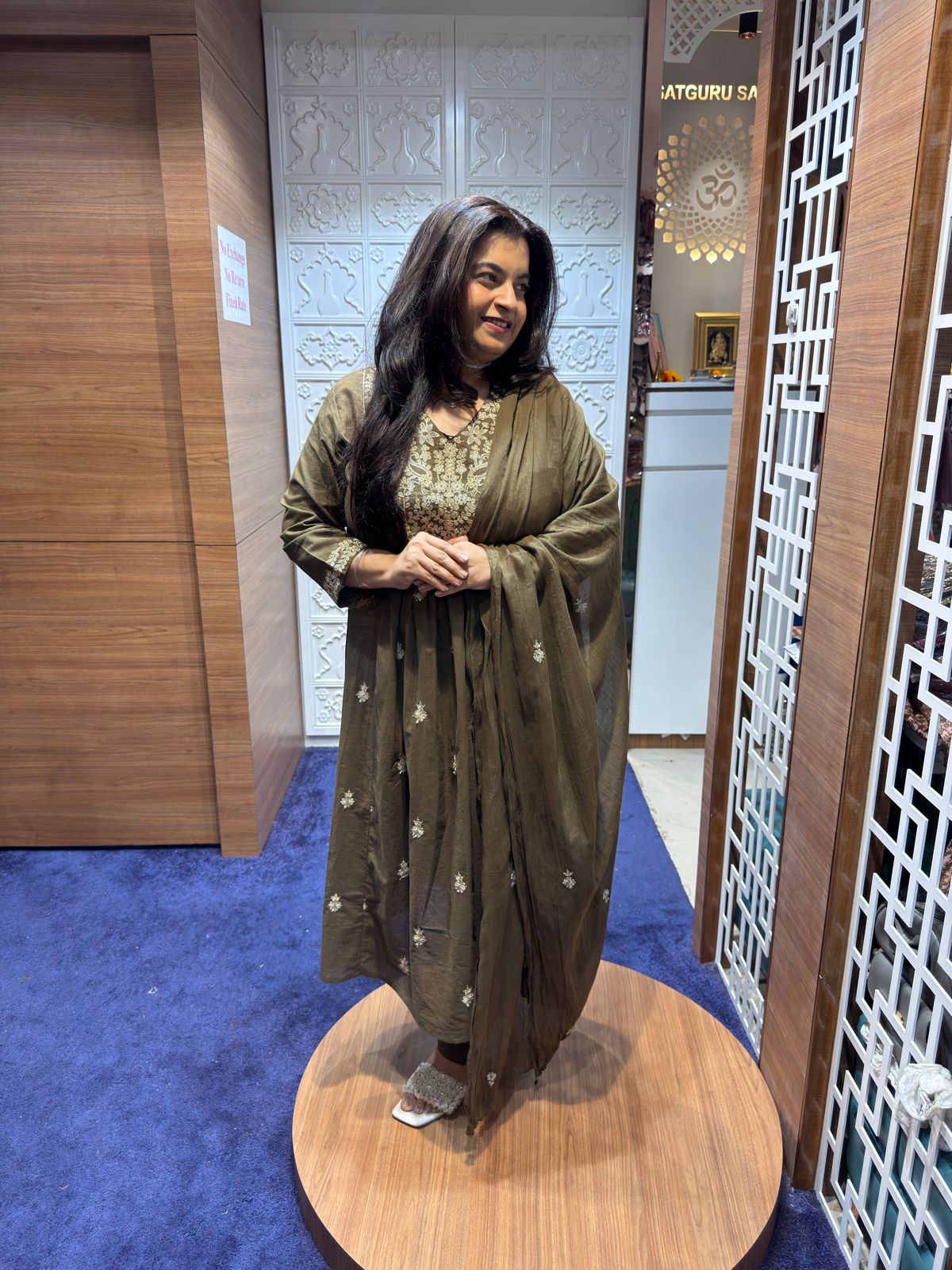 Woman in a green traditional outfit standing in front of a mirror.